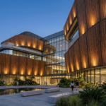 A modern eco-friendly commercial building featuring a sustainable bamboo wall facade with architectural lighting at dusk.